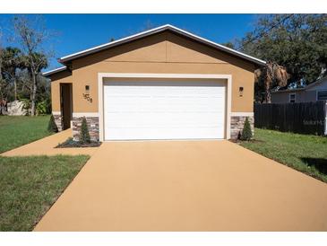Home's exterior with a two-car garage, stone accents, fresh paint, new driveway and manicured landscaping at 1508 W 16Th St, Sanford, FL 32771