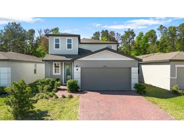 Charming two-story home featuring a red brick driveway, a two-car garage, and well-maintained landscaping at 17411 Million Lakes Ct, Clermont, FL 34714