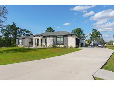 Beautiful home exterior featuring manicured lawn, stone accents, and a long driveway at 18721 Seaview St, Orlando, FL 32833