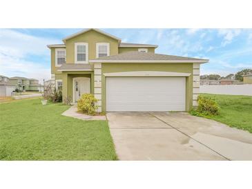 Charming two-story home with a two-car garage, manicured lawn, and lush landscaping at 2311 Whitley Ln, Winter Haven, FL 33881