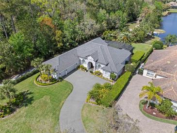 Stunning aerial view of a luxurious home with lush landscaping, a large driveway, and a glimpse of a serene lake at 3340 Fernlake Pl, Longwood, FL 32779