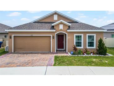 Tan single-story home with a red-brick driveway, tidy landscaping, and an attached two-car garage at 434 Ironside Trail Dr, Groveland, FL 34736