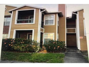 Exterior view of a two-story condo with a walkway and small front yard with orange flowers at 4350 Perkinshire Ln # 108, Orlando, FL 32822