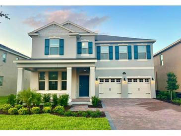 Charming two-story home featuring a manicured lawn, a two-car garage, and a welcoming front porch at 18381 Oliver Twist Way, Winter Garden, FL 34787