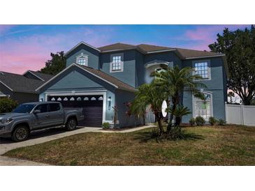 Charming two-story home with an attached garage, well-manicured lawn and tasteful landscaping with tropical plants at 2204 Hammock Moss Dr, Orlando, FL 32820