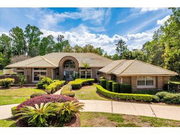 Stunning brick home with a tan tile roof and meticulously manicured landscaping at 2733 Deer Berry Ct, Longwood, FL 32779