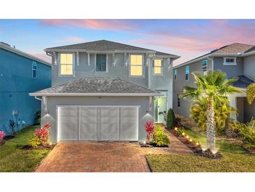 Charming two-story home with a well-manicured lawn and an illuminated brick driveway at twilight at 3964 Lightning Ct, Sanford, FL 32773