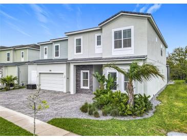 Beautifully landscaped home featuring a two-car garage and a combination of stone and stucco finishes at 1739 Oak Blossom Dr, Davenport, FL 33837