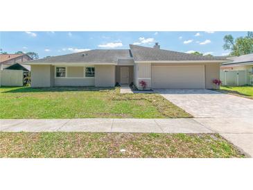 Charming single-story home with a manicured lawn and a paved driveway leading to an attached two-car garage at 323 Shadow Oak Dr, Casselberry, FL 32707