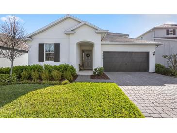 Inviting home featuring a manicured lawn, neutral colors, a two-car garage and stylish shutters at 4418 Lions Gate Ave, Clermont, FL 34711