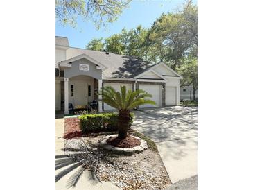 Charming condo exterior with multiple garages, stone accents, and beautiful landscaping with a small palm tree at 1010 Loch Vail # 1125, Apopka, FL 32712