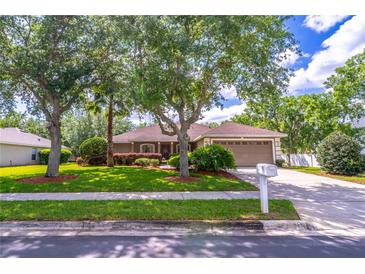 Charming single-story home featuring a well-manicured lawn, mature trees, and a two-car garage at 1272 Mount Logan Dr, Apopka, FL 32712