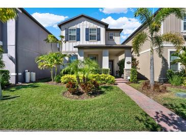 Charming two-story home features a well-manicured lawn, lush landscaping, and a welcoming brick pathway to the front porch at 17055 Wynford Ln, Winter Garden, FL 34787