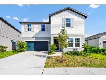 Charming two-story home with a blue garage door, landscaped yard, and a combination of white and gray siding at 2126 Derwent Dr, Davenport, FL 33896