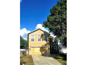 Two-story home featuring an attached garage, well-maintained lawn, and large tree at 25012 Chipshot Ct, Sorrento, FL 32776