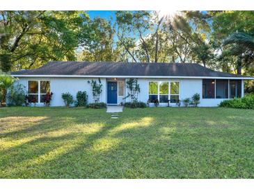 Charming one-story home featuring a well-maintained lawn, mature trees, and a welcoming entrance with a blue door at 31024 Prestwick Ave, Sorrento, FL 32776