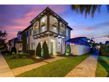 Stunning two story exterior with balcony, manicured landscaping and a beautiful sunset sky above the residence at 8872 Bismarck Palm Dr, Winter Garden, FL 34787