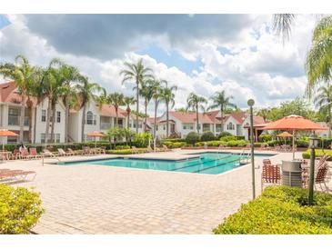 Community pool and deck surrounded by lush landscaping and lounge chairs at 11562 Westwood Blvd # 934, Orlando, FL 32821