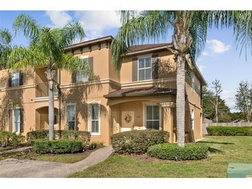 Two-story townhouse with tan exterior, manicured landscaping and healthy palm trees at 302 Calabria Ave, Davenport, FL 33897