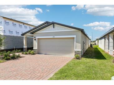 Charming single-story home features a brick driveway, light-colored exterior, and a two-car garage on a sunny day at 4973 Kaia Ave, Winter Haven, FL 33884