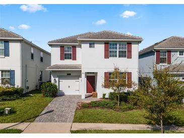 Charming two-story home featuring a well-manicured lawn and a red front door and red shutters at 1565 Mulligan Blvd, Davenport, FL 33896