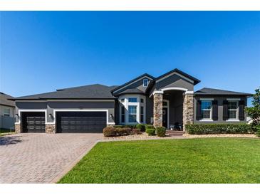 Beautiful home featuring stone accents, well-maintained landscaping, and a three-car garage at 16003 Tangerine Blossom Way, Winter Garden, FL 34787