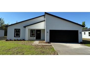 Modern single-story home featuring a black two-car garage, minimalist landscaping, and bright white stucco exterior at 168 Marion Oaks Ln, Ocala, FL 34473