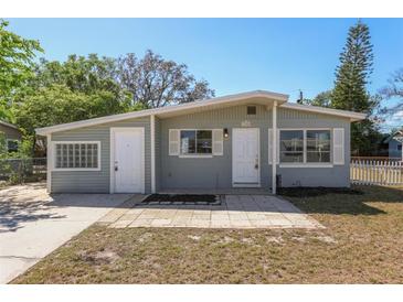 Charming single-story home with a light grey exterior, complemented by white trim, shutters, and a well-maintained front yard at 2318 Vincent Rd, Orlando, FL 32817