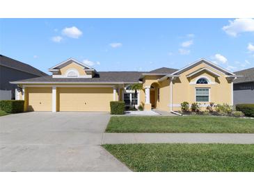 Charming yellow home with a well-manicured lawn and a three-car garage at 419 Coventry Rd, Davenport, FL 33897