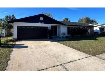 Charming single-story home featuring a black garage door, a well-maintained lawn, and an inviting front entrance at 6130 Gamble Dr, Orlando, FL 32808