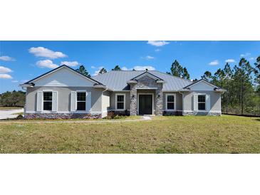 Charming single-story home with stone accents, a metal roof and shutters on a well-maintained lawn at 947 Ferne Dr, Longwood, FL 32779