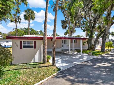 Single-story home with a covered carport and mature landscaping, and a charming facade at 105 Canal Vw, Eustis, FL 32726