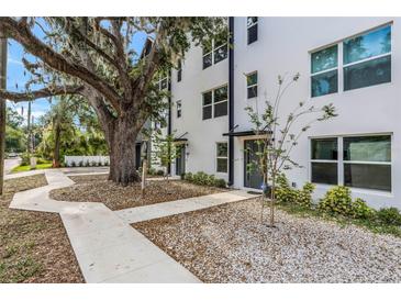 Modern townhome shows striking elevation with mature tree, neutral colors, and inviting front entrance at 1602 Park Lake St # 2, Orlando, FL 32803
