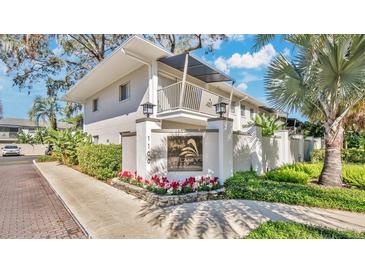 Beautiful condo exterior view with a garden and building sign under a bright blue sky with light clouds at 1100 Delaney Ave # E13, Orlando, FL 32806