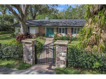 Charming single-story brick home with a manicured lawn, stone pillars, and beautiful turquoise double front doors at 137 Tangerine Ave, Oviedo, FL 32765