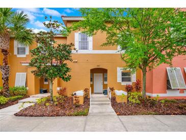 Inviting townhouse with a warm, golden exterior, landscaped front yard, and a welcoming entrance at 141 Pompano Beach Dr, Kissimmee, FL 34746