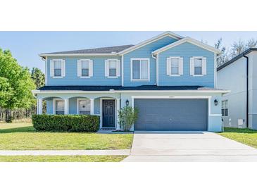 Charming two-story home with blue siding, white trim, manicured lawn, and a spacious two-car garage at 16805 Sunrise Vista Dr, Clermont, FL 34714