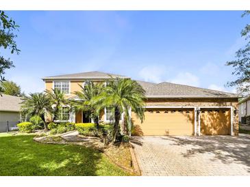 Beautiful two-story house with a three-car garage, a well-manicured lawn and mature landscaping at 3780 Woodhurst Ct, Oviedo, FL 32766