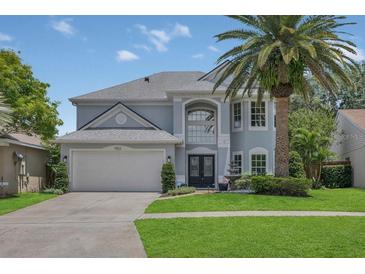 Charming two-story home with a well-manicured lawn, beautiful landscaping, and a large palm tree at 1923 Osman Ave, Orlando, FL 32806