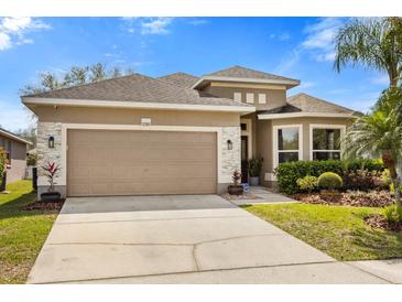 Charming single-Gathering home with a beige exterior, landscaped yard, and a two-car garage in a sunny, residential neighborhood at 2315 Cypress Trace Cir, Orlando, FL 32825