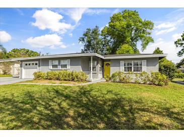 Charming gray brick home featuring a bright yellow front door and manicured front lawn at 520 Oriole Dr, Lakeland, FL 33803