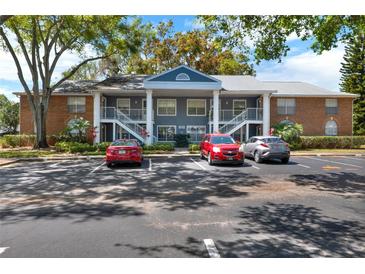 Condo building with brick accents, white railings, and ample parking at 5429 Lake Margaret Dr # 185, Orlando, FL 32812