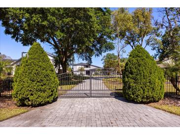 Gated driveway leads to an elegant home surrounded by mature landscaping at 7841 Georgeann St, Winter Park, FL 32792