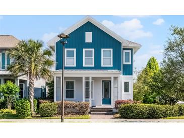Charming two-story home features a light blue exterior, well-manicured landscaping, and a welcoming front porch at 13087 Salk Way, Orlando, FL 32827