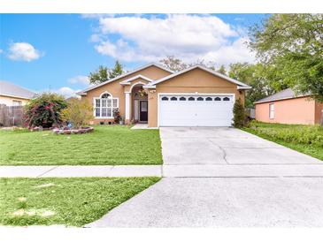 Charming single-story home featuring a well-maintained lawn and a two-car garage in a residential neighborhood at 1562 Woodwind Dr, Apopka, FL 32703