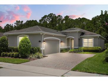 Charming single-story home featuring a brick driveway, two-car garage, manicured landscaping, and a neutral color palette at 1686 Victoria Gardens Dr, Deland, FL 32724