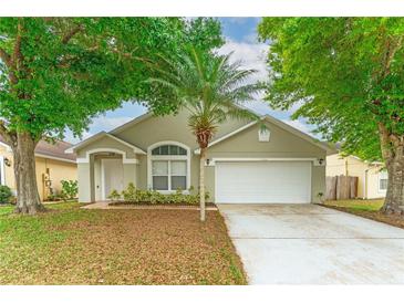 Charming single-story home featuring a well-manicured lawn, mature trees, and a two-car garage at 2104 Remington Pointe Blvd, Kissimmee, FL 34743