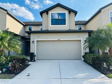 Charming townhome with a two-car garage, beautiful landscaping, and a well-lit driveway on a sunny day at 2285 Seven Oaks Dr, St Cloud, FL 34772