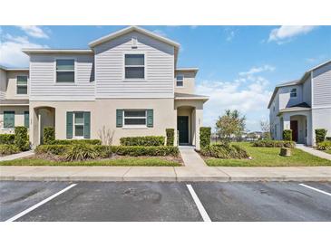Charming two-story townhome featuring lush landscaping, with a inviting entrance and convenient parking spaces at 233 Primrose Dr, Davenport, FL 33837