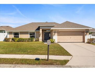 Charming single-story home with well-maintained lawn, beige exterior, and a two-car garage, offering curb appeal at 2412 Twin Lake View Rd, Winter Haven, FL 33881